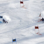 Two skiers are racing against each other in a parallel.