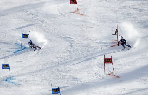 Two skiers are racing against each other in a parallel.